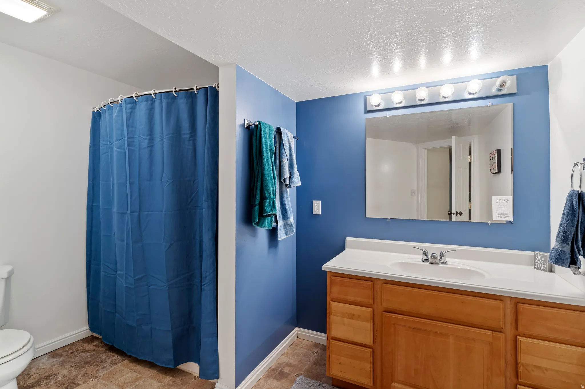 Bathroom featuring a single vanity with wood-finish cabinetry, a white countertop, and an integrated sink