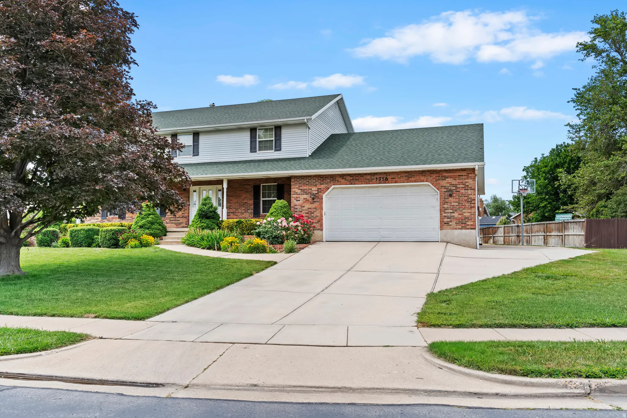 Two-story residence featuring a brick facade, light-colored siding, and a two-car garage with a concrete driveway