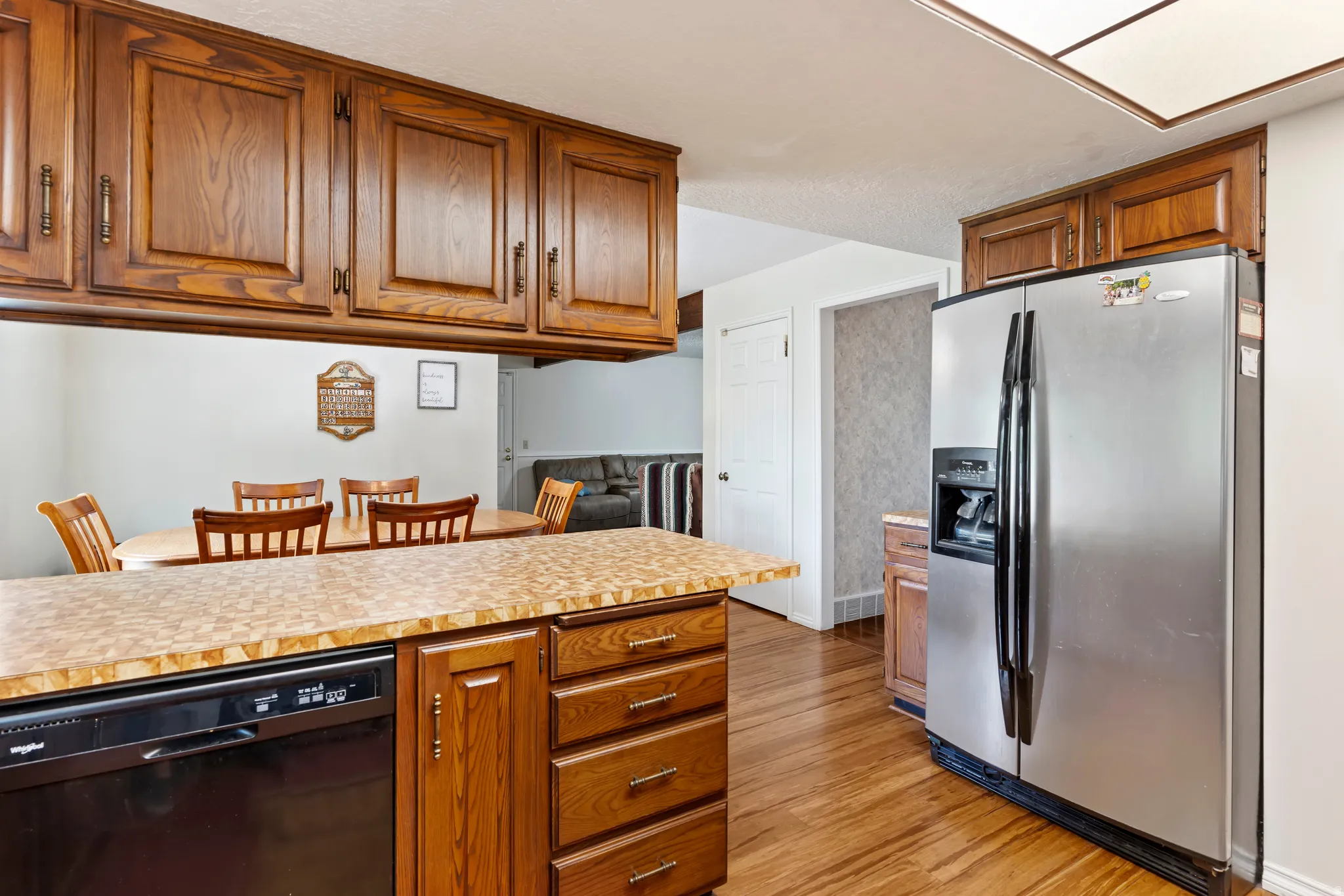 Kitchen featuring wood-finish cabinetry, a stainless steel side-by-side refrigerator, and a built-in black dishwasher