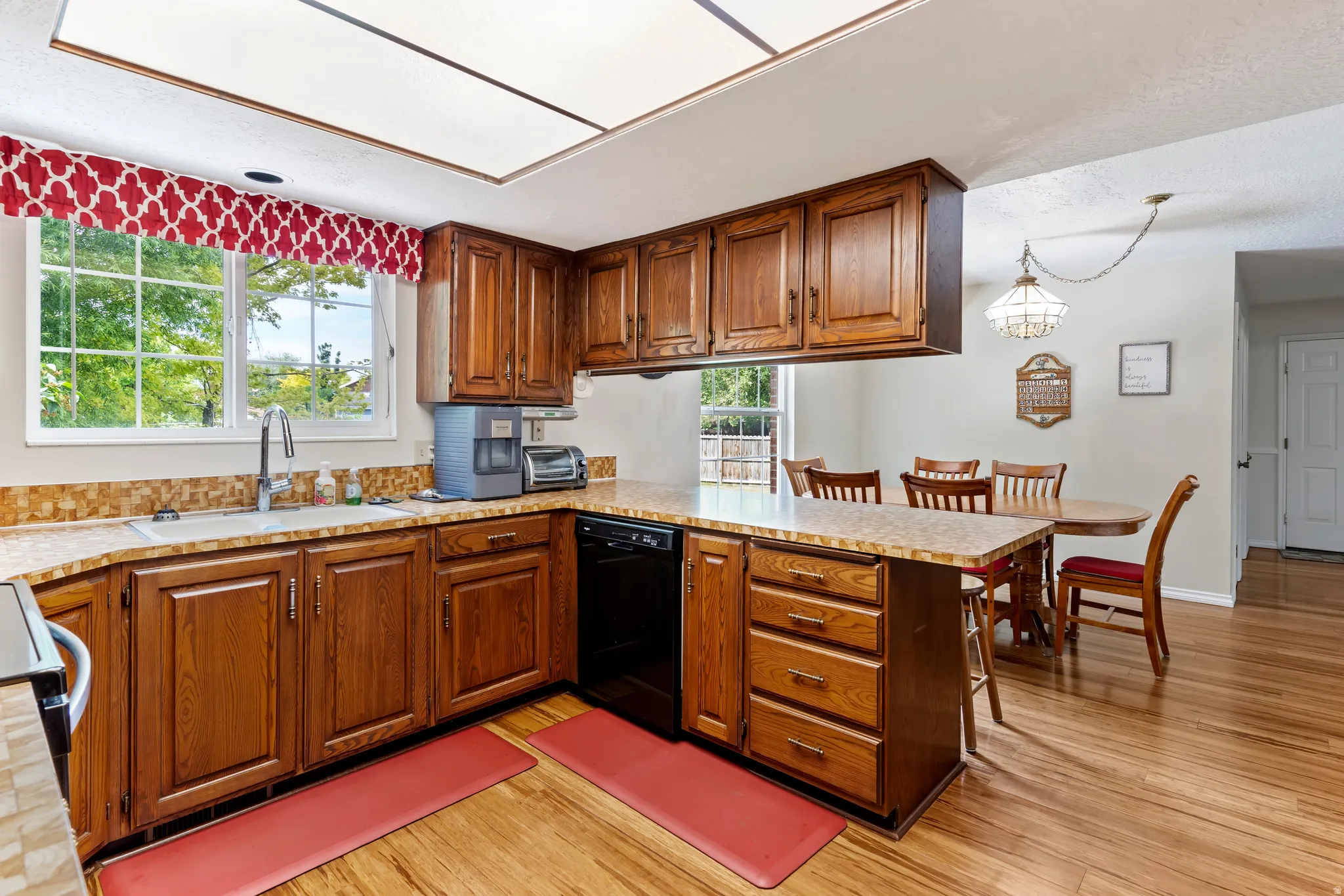 Kitchen featuring wood cabinetry, a built-in dishwasher, and a double basin sink
