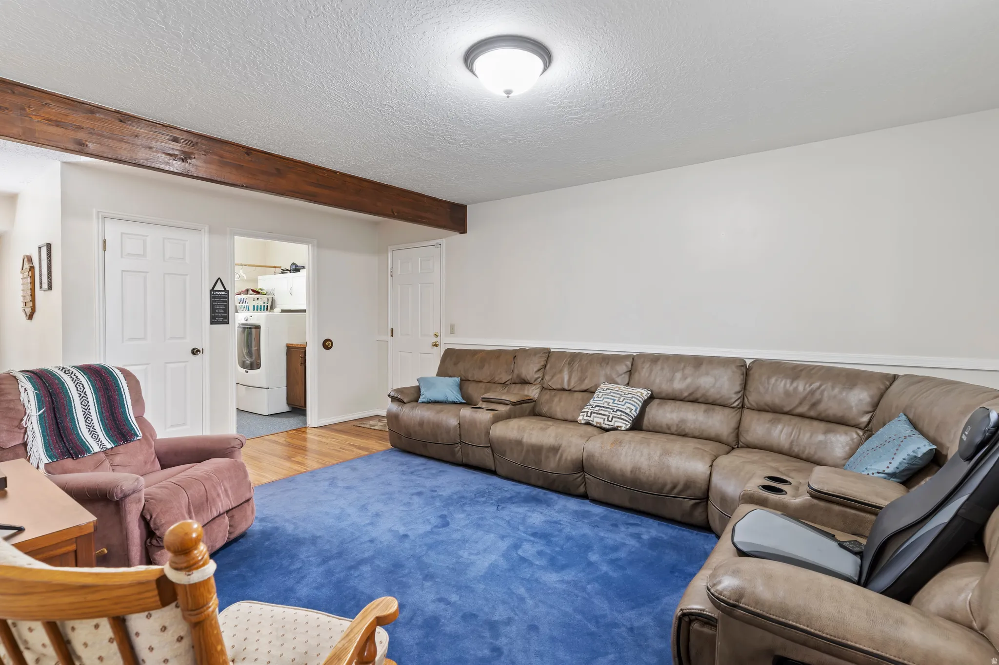 Finished room featuring exposed wood beam, white walls, and a ceiling-mounted light fixture
