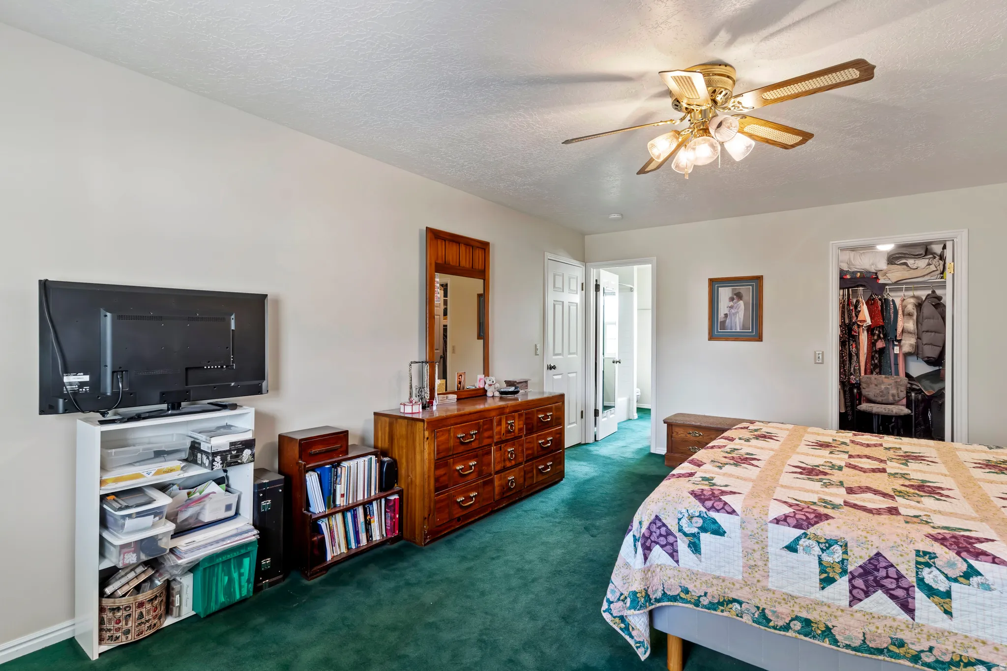Bedroom featuring deep green carpeting, white walls, and a ceiling fan with integrated lighting
