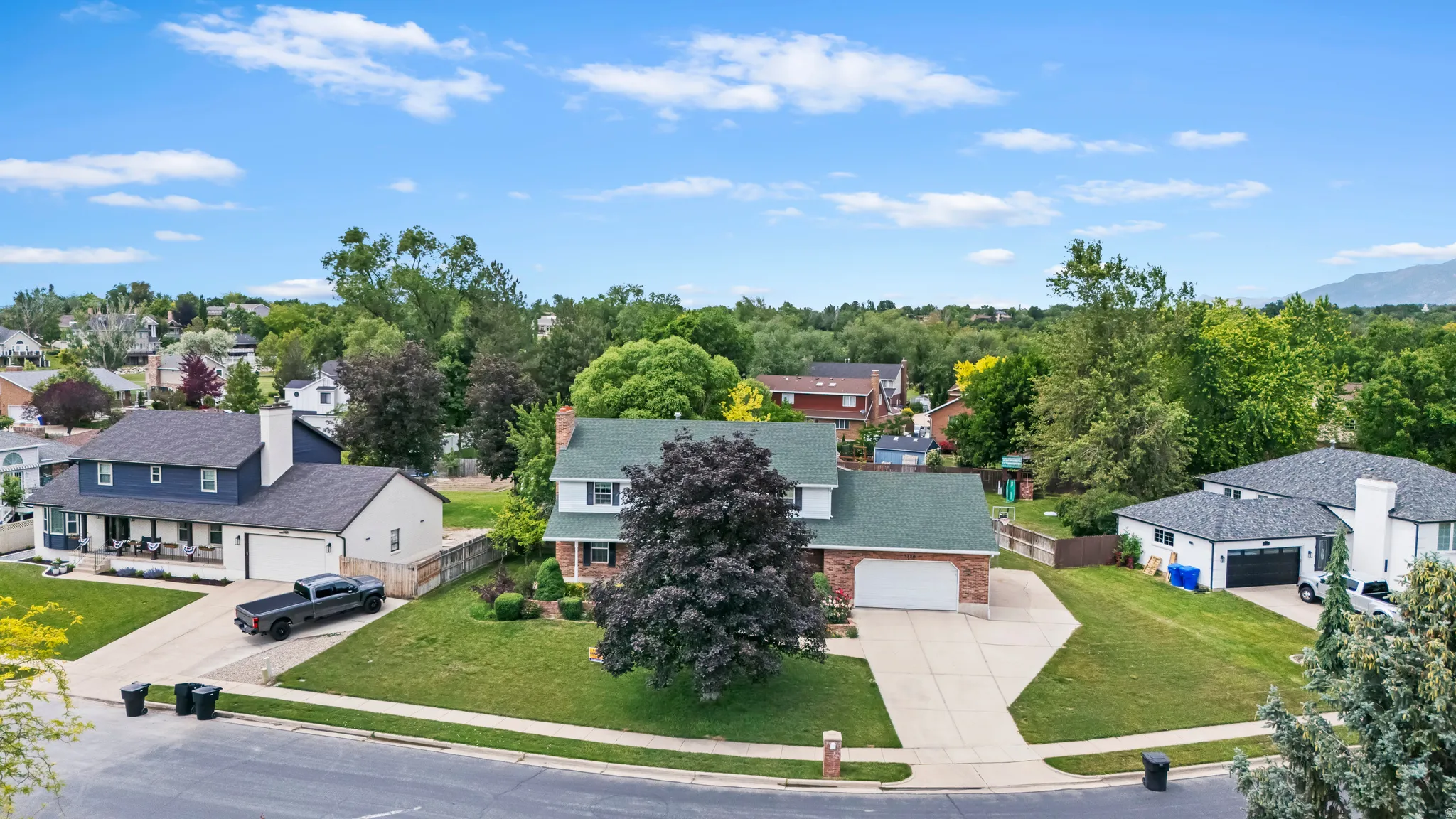 Brick exterior residence with a two-car garage, mature landscaping, and an expansive front lawn
