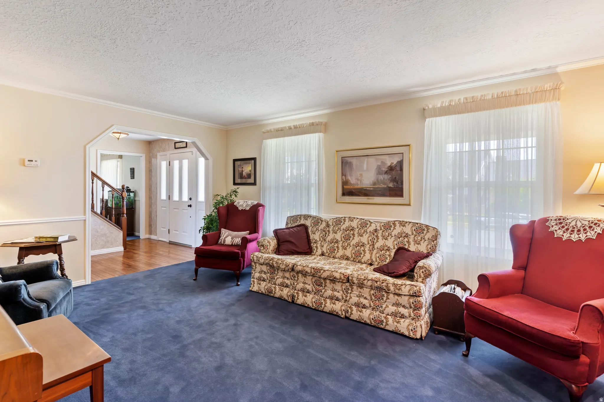 Spacious living area featuring blue carpeting, light-toned walls, and white crown molding