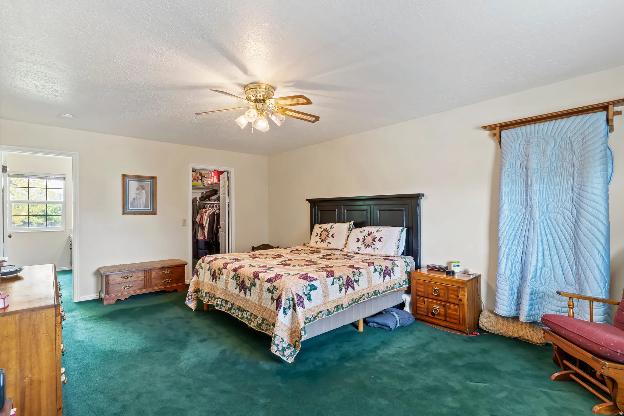 Spacious room featuring green carpeting, a ceiling fan with integrated lighting, and a closet with bifold doors