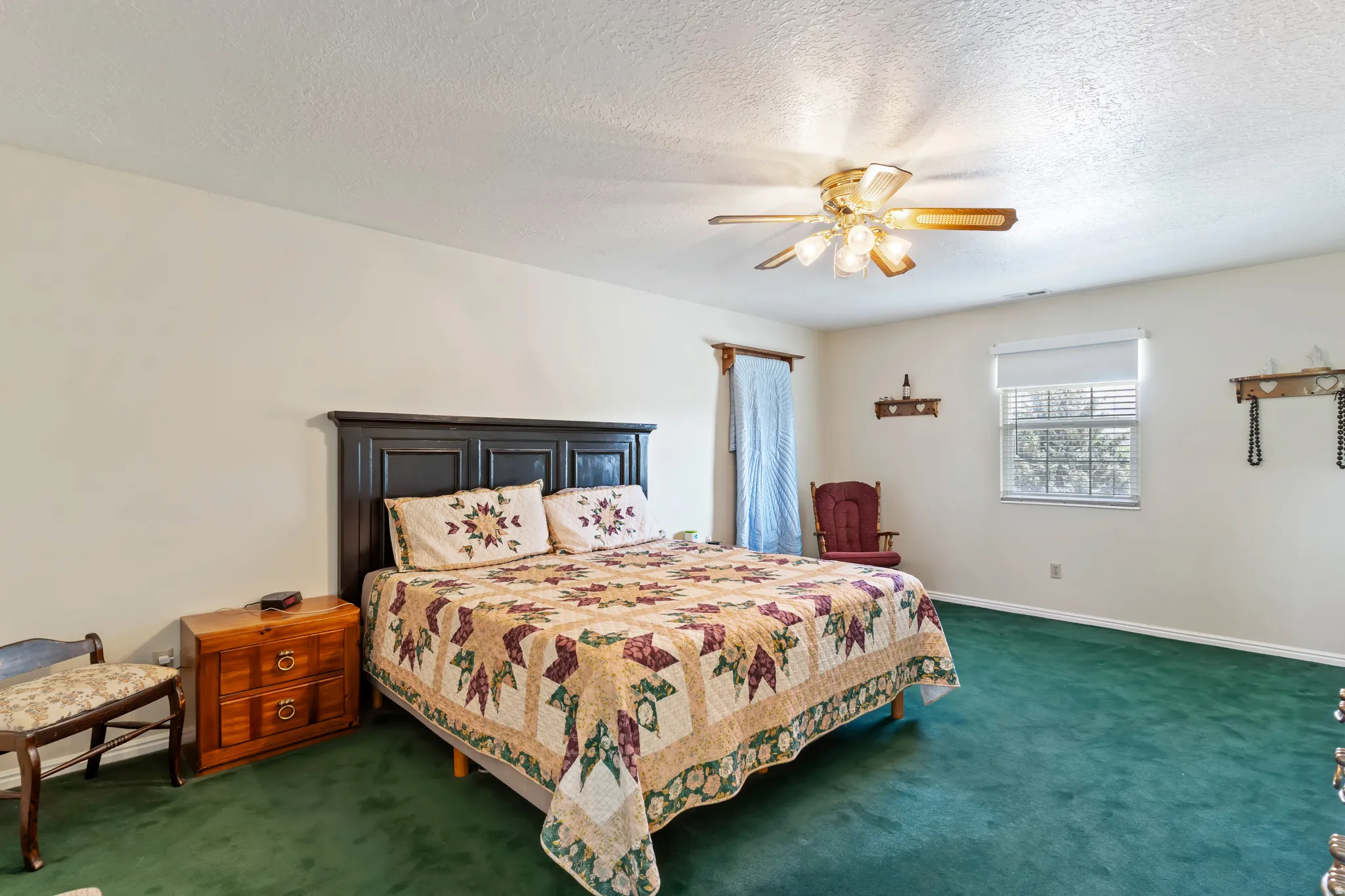 Spacious room featuring broadloom carpet, a ceiling fan with integrated lighting, a window with blinds, and white painted walls