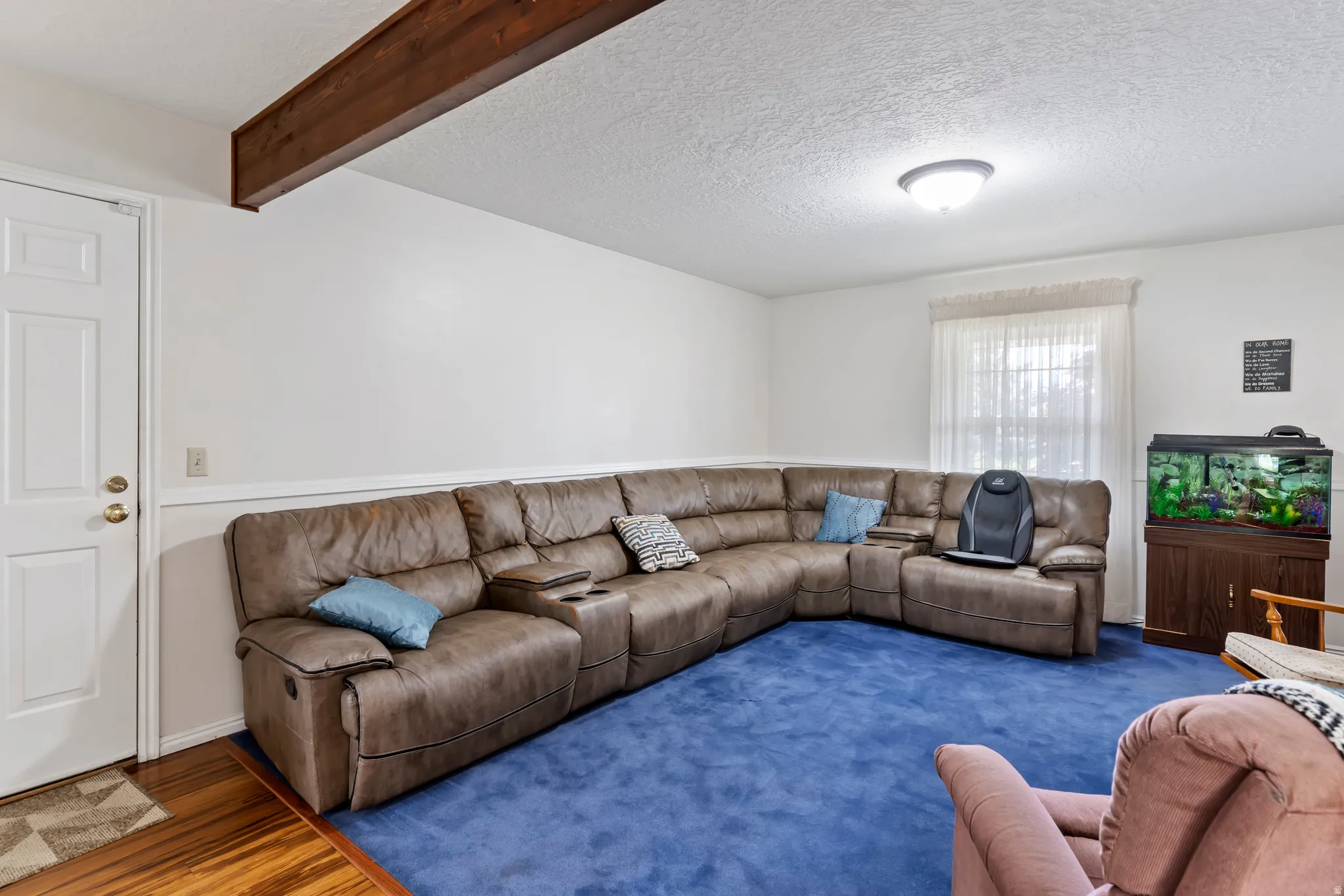 Room with white walls, a single window with curtain, and a wood-finish ceiling beam