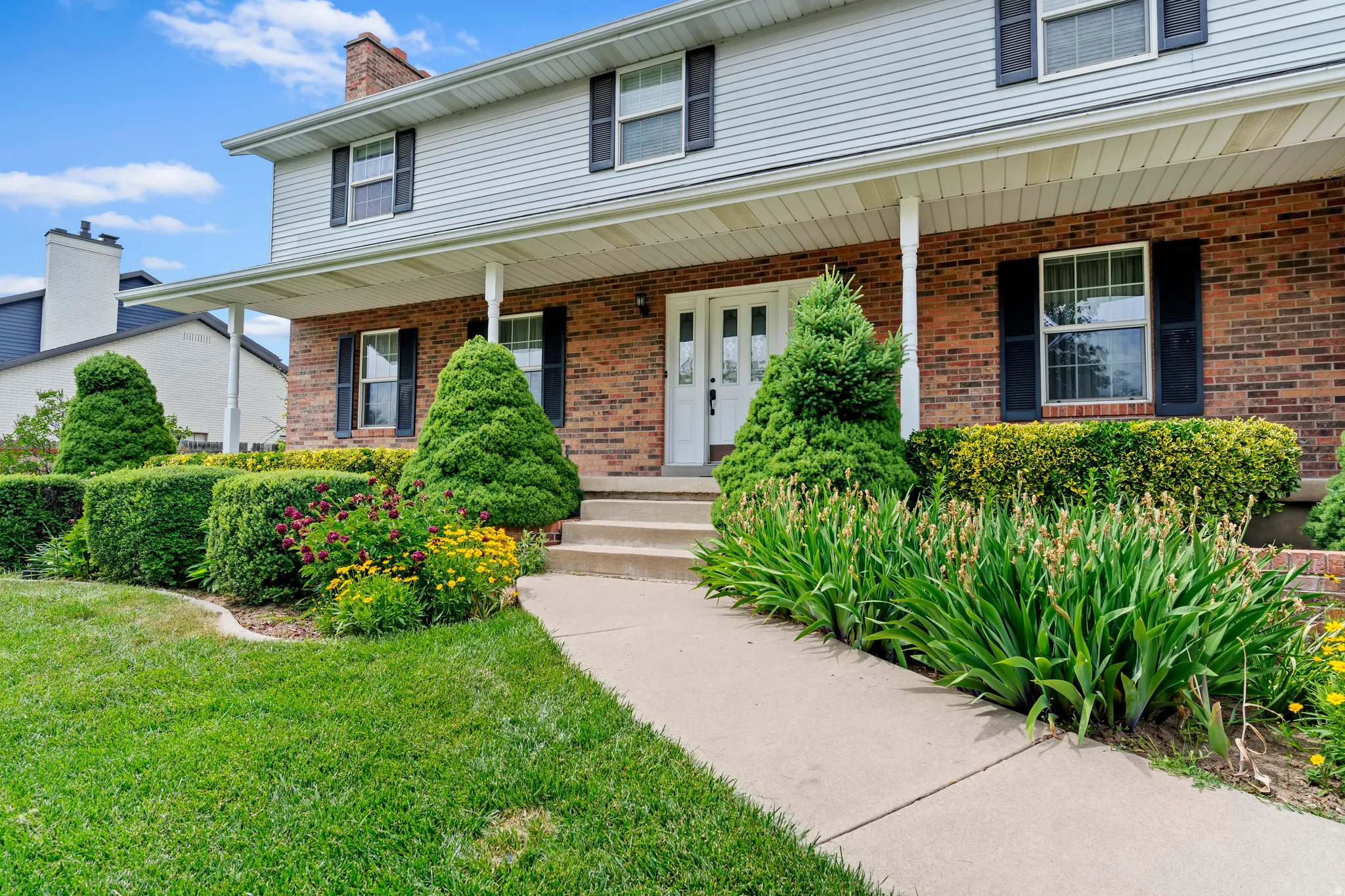 Brick and siding exterior featuring a covered front porch with white columns