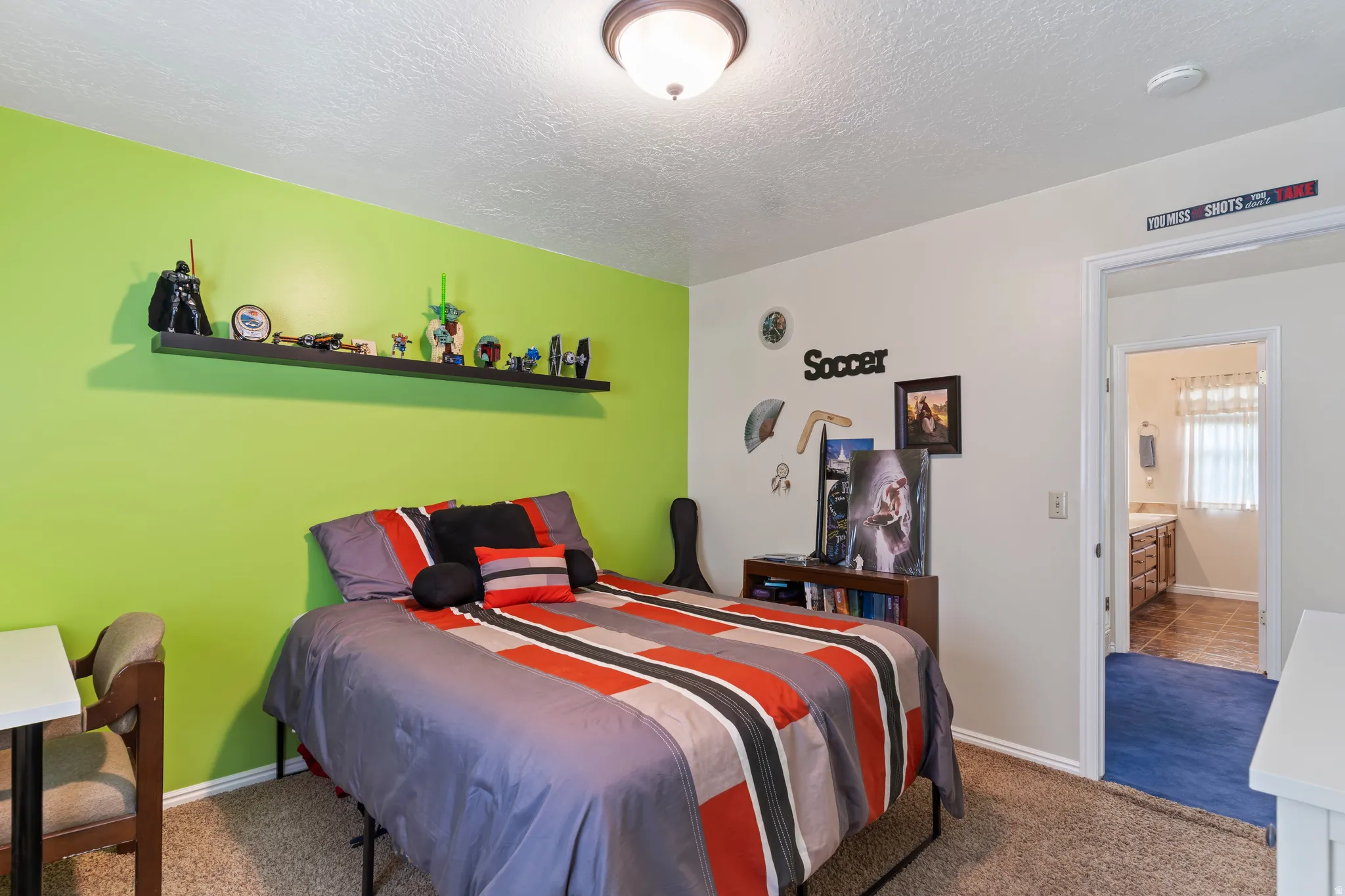 Bedroom featuring a vibrant accent wall, neutral wall tones, and carpeted flooring