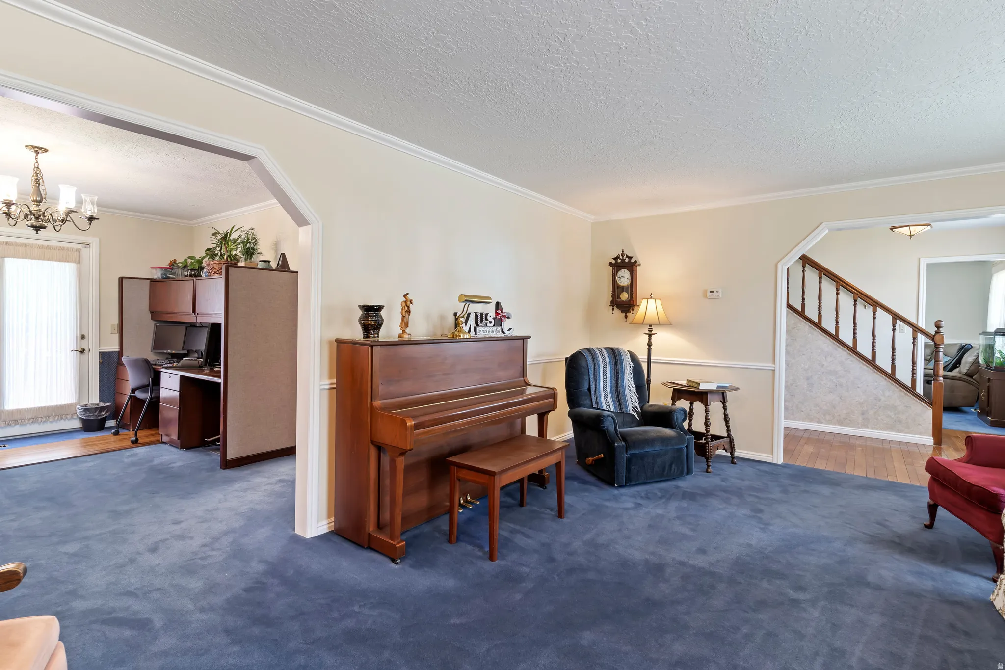 Archway entry from a carpeted room featuring crown molding and chair rail detailing