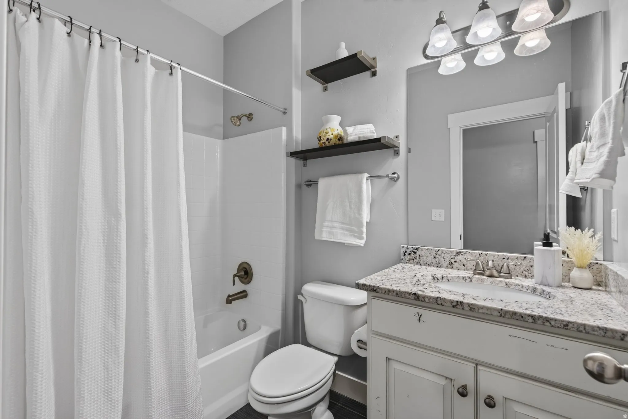 Main level full guest bathroom with granite countertops, tiles floors, and tub/shower surround.
