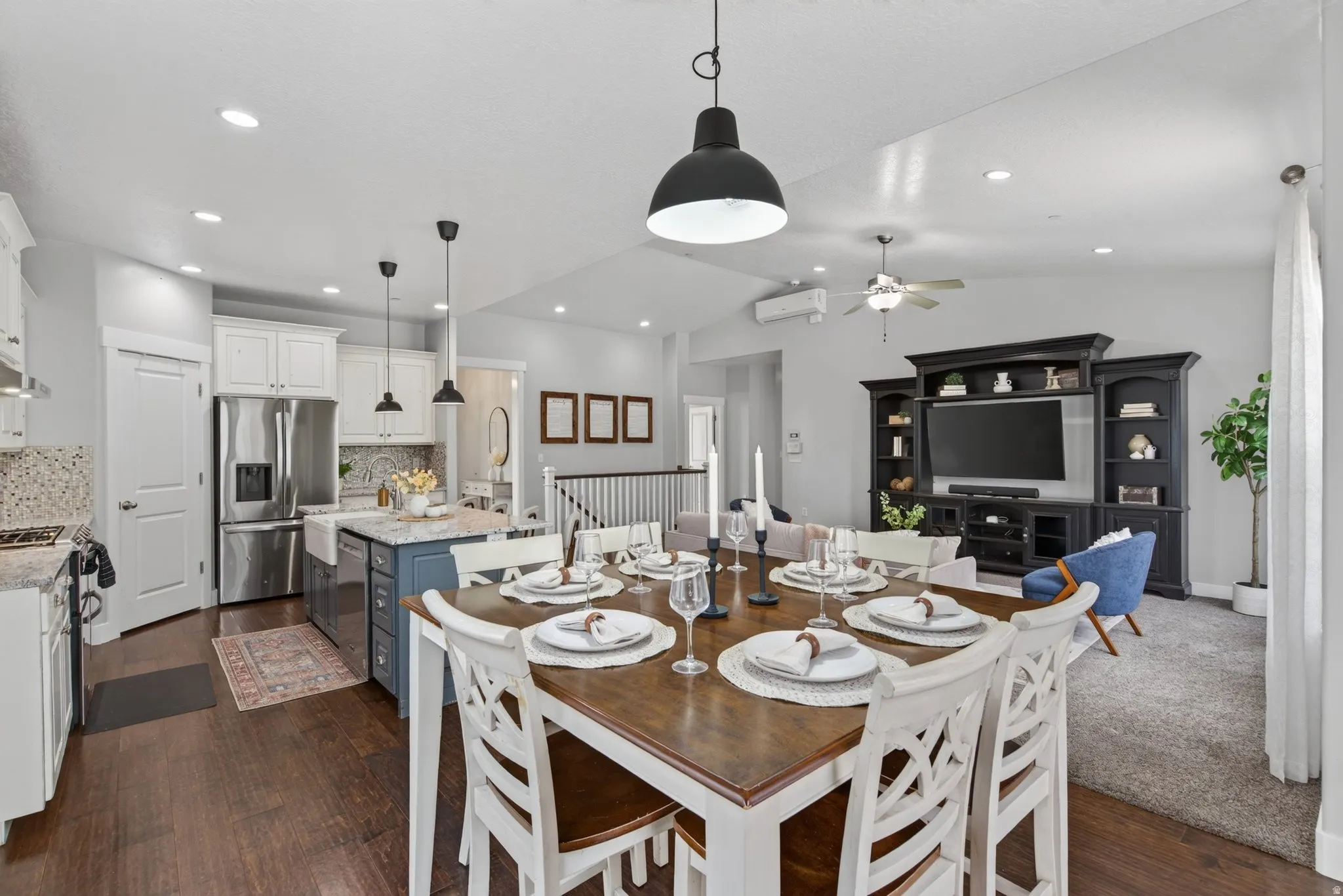 Open-concept kitchen, dining, and living area with island seating, natural light, backyard views, and a comfortable layout for gathering.