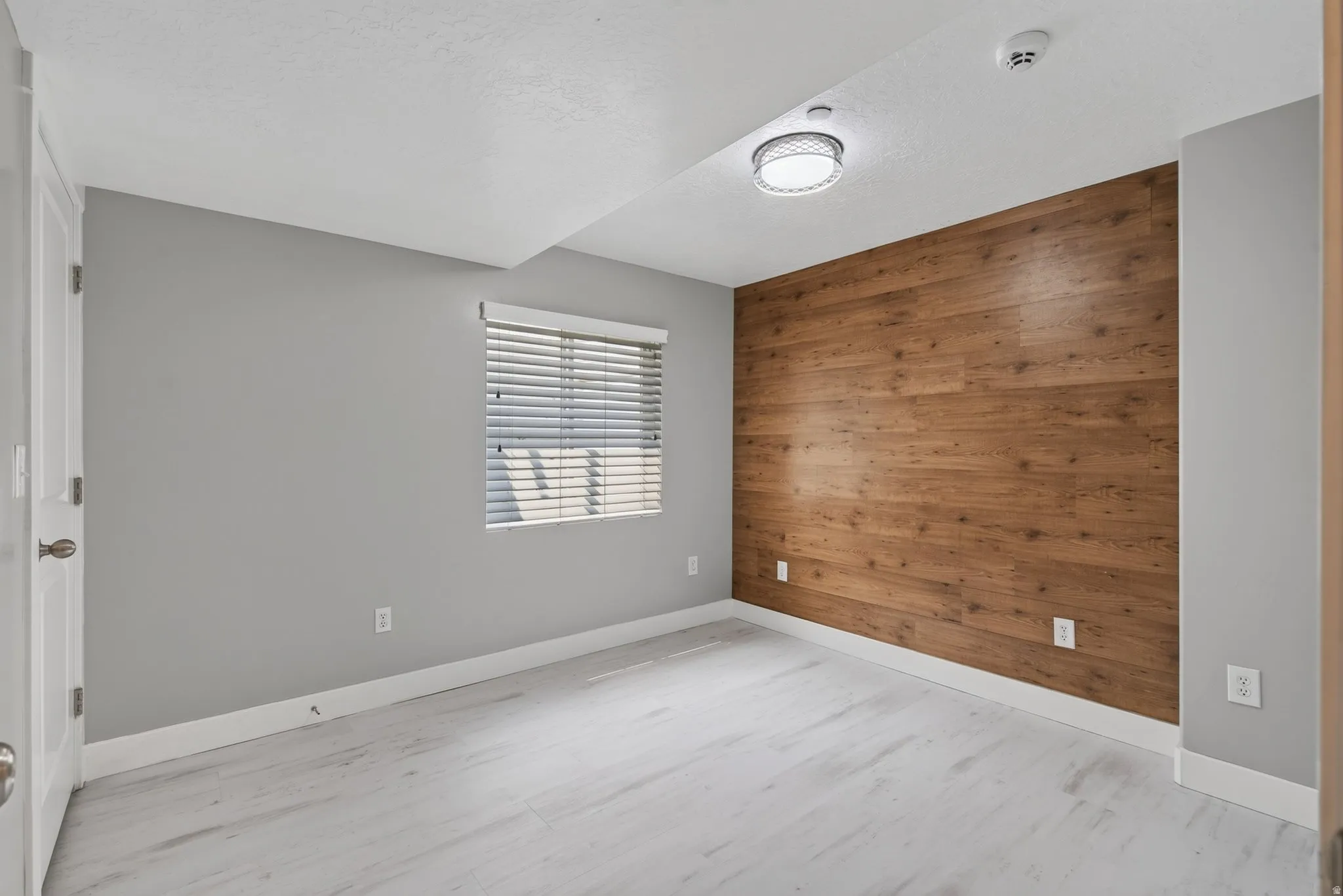 Basement bedroom 1 of 3 currently used as an office. Accent wall featuring horizontal wood-finish planks and luxury vinyl plank flooring with closet.