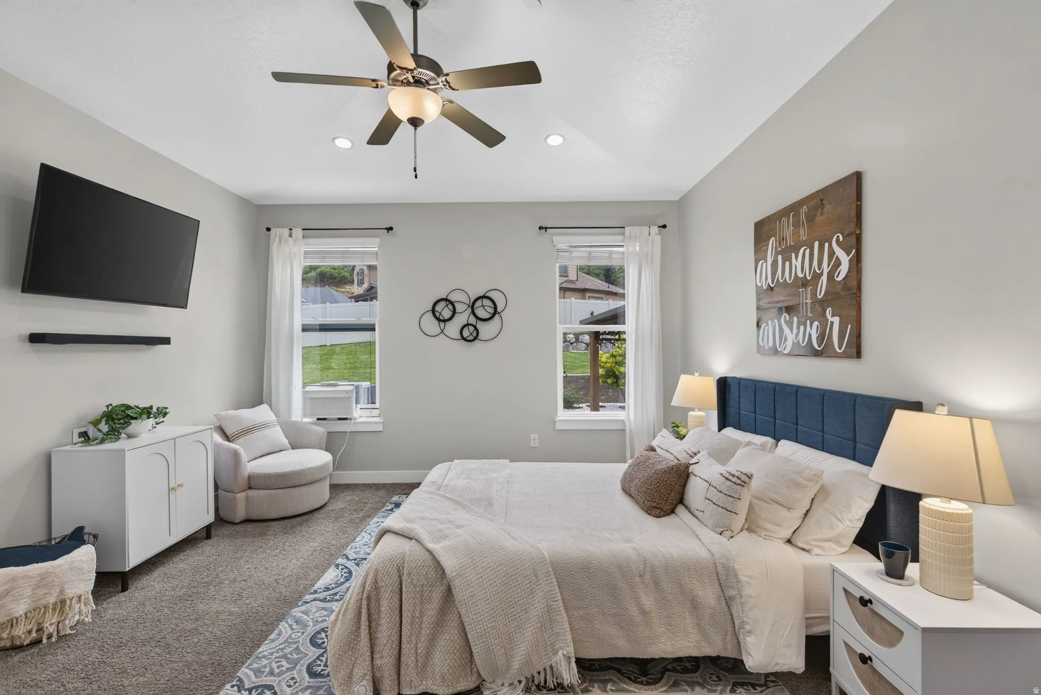 Main level living for the master bedroom with natural light, ceiling fan, neutral finishes, and plenty of space for a queen or king bed and dressers. Window A/C unit included for isolated multi zone comfort.