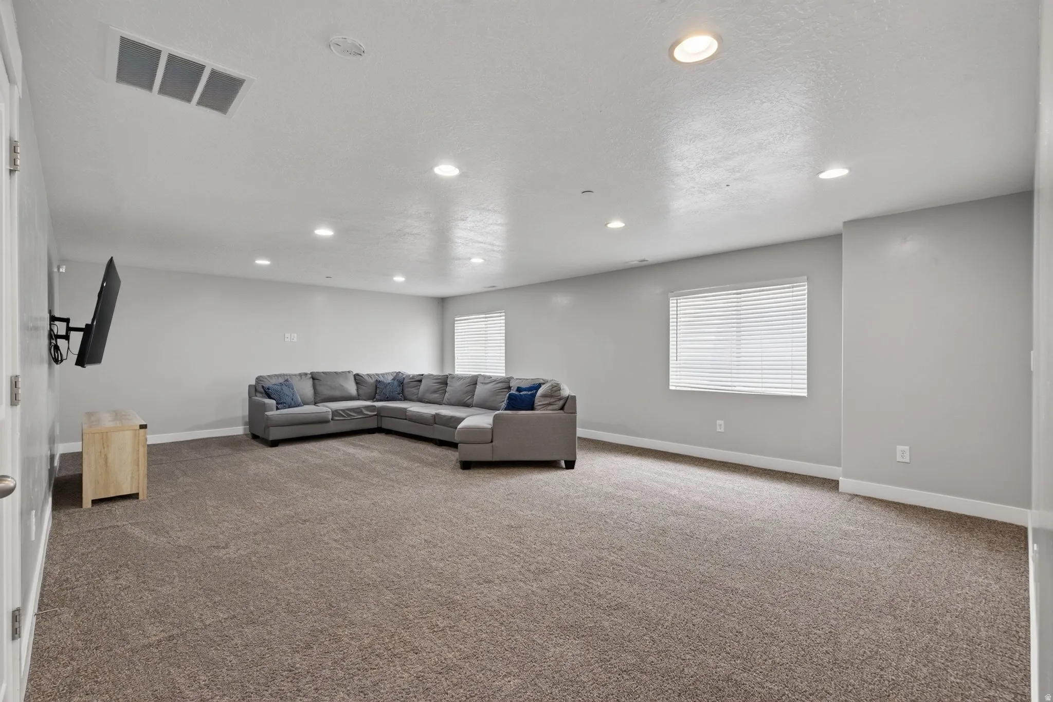 Basement level family room - spacious recreation area featuring neutral tone carpeting and light gray walls