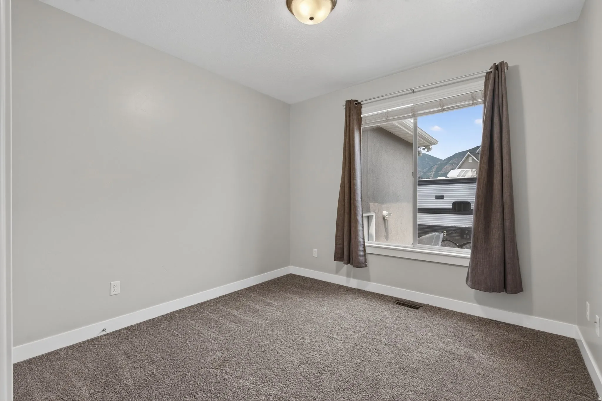 2nd of 3 main floor bedrooms - light gray walls with white trim and a large window with white framing