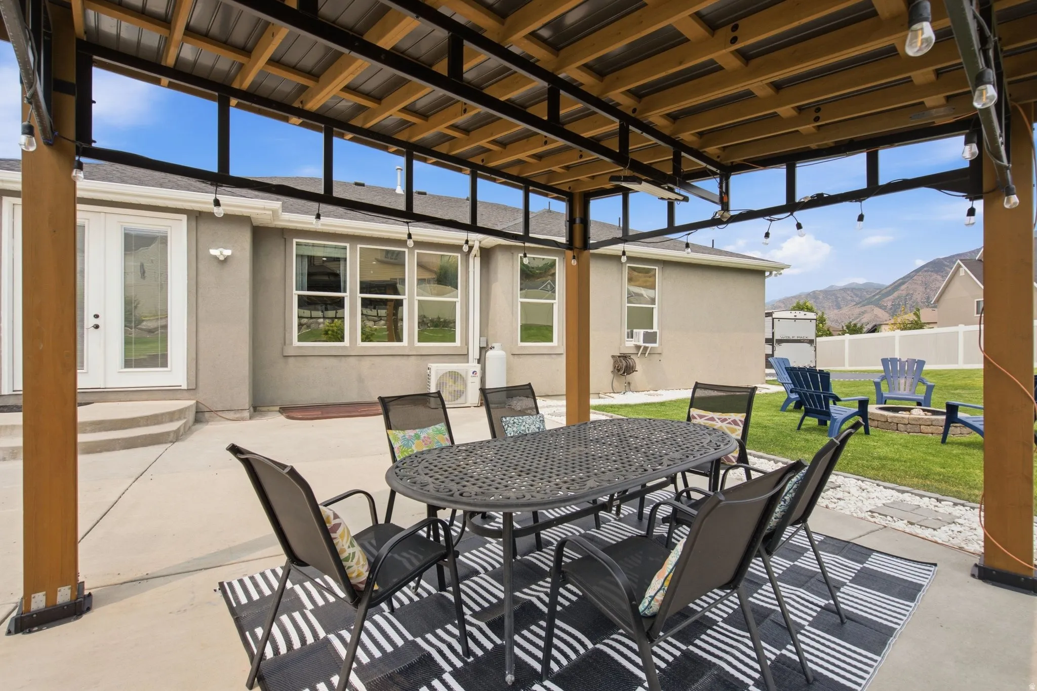 Covered patio with string lighting, concrete flooring, and a corrugated metal roof