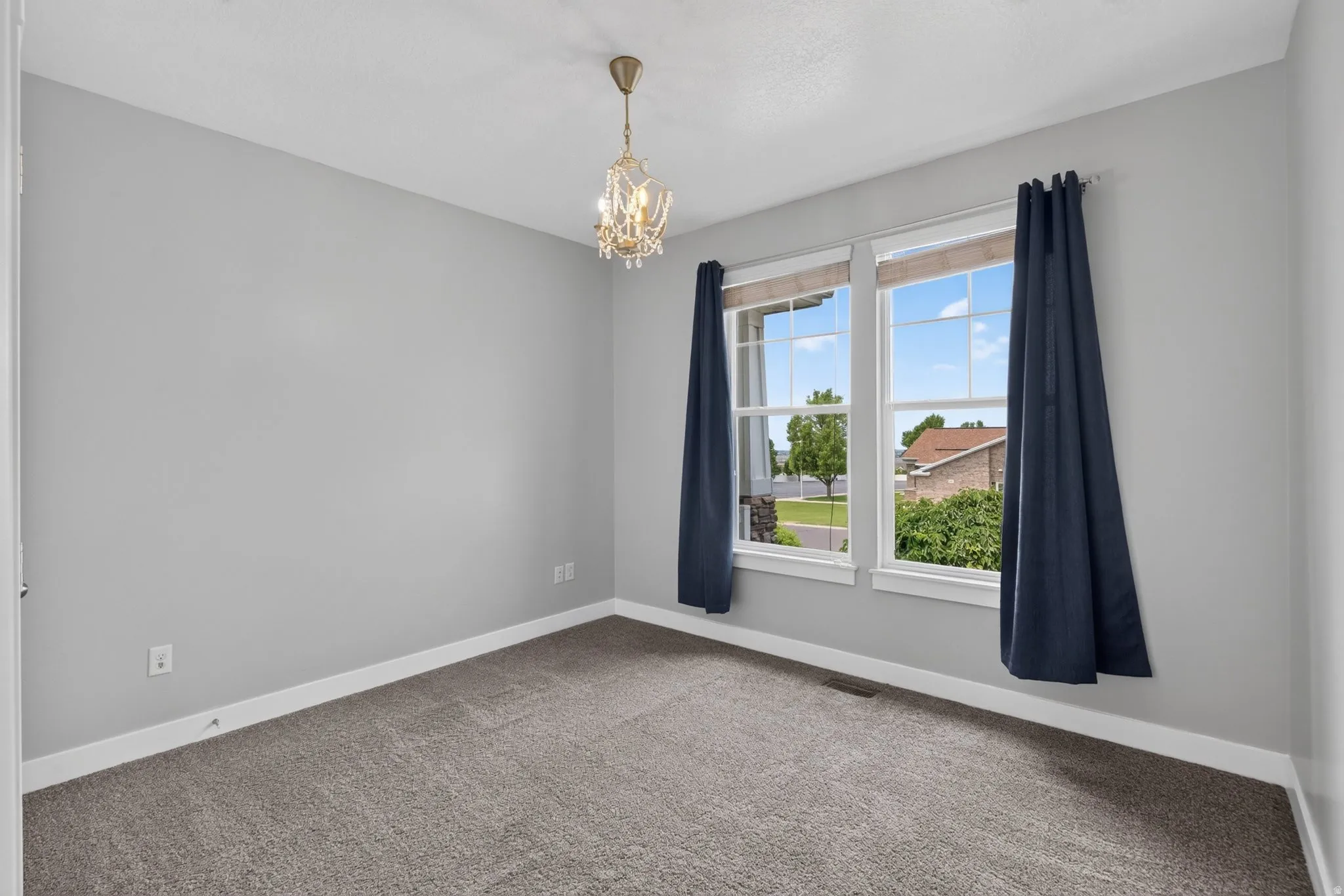 3rd of 3 main floor bedrooms - large windows create plenty of natural light, a closet, two large windows, and a decorative light fixture.