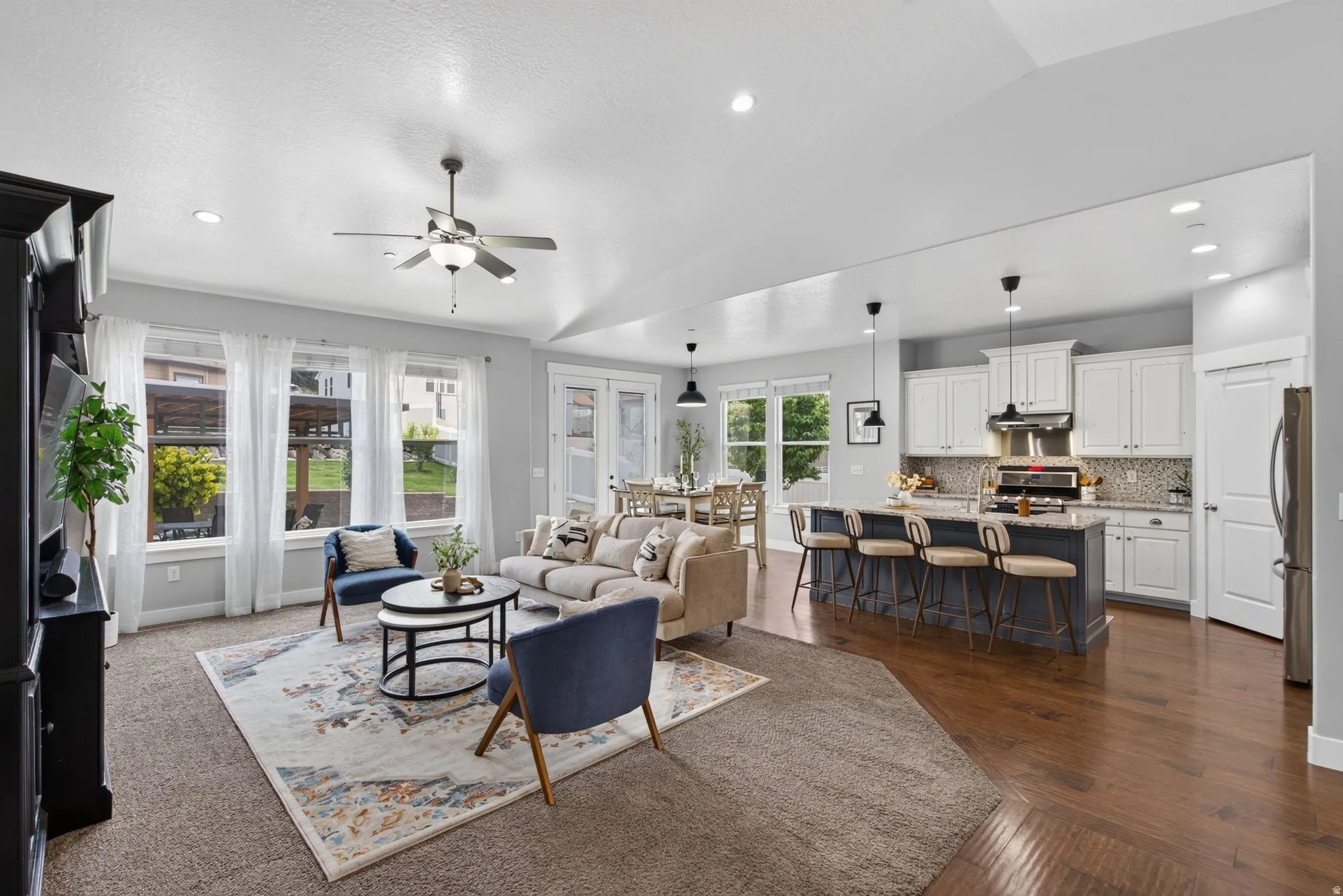 Spacious open living area connecting the kitchen, dining, and family room with bright windows, island seating, and backyard views.