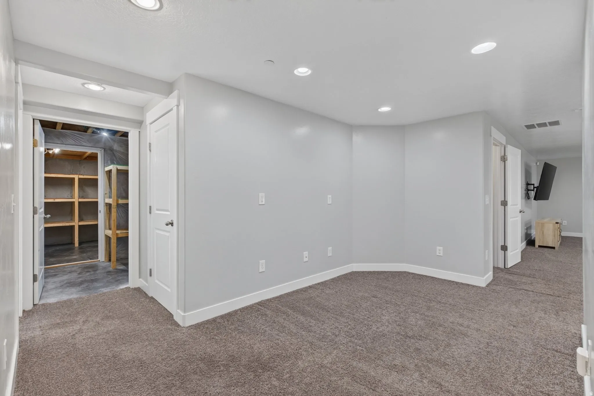Entryway area of basement near to 3 bedrooms and basement bathroom. Carpeted room with recessed lighting and light gray walls