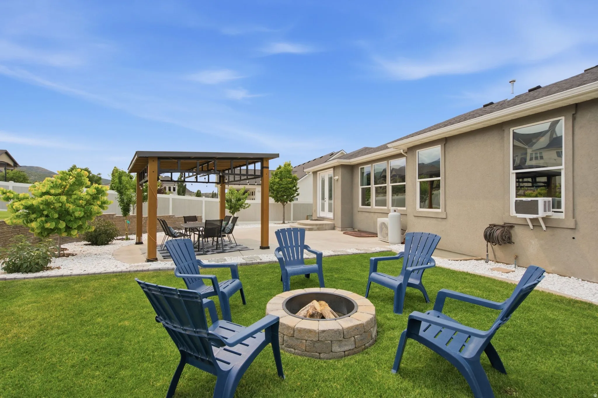 Backyard oasis with covered gazebo, stone fire pit, patio seating, updated landscaping, and space designed for outdoor dining and relaxing.