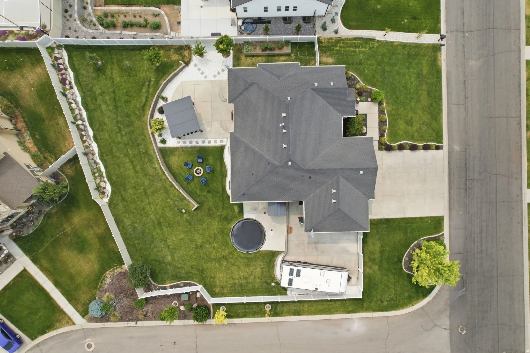 Expansive property featuring a dark-shingled roof, a concrete driveway, and a large grassy yard