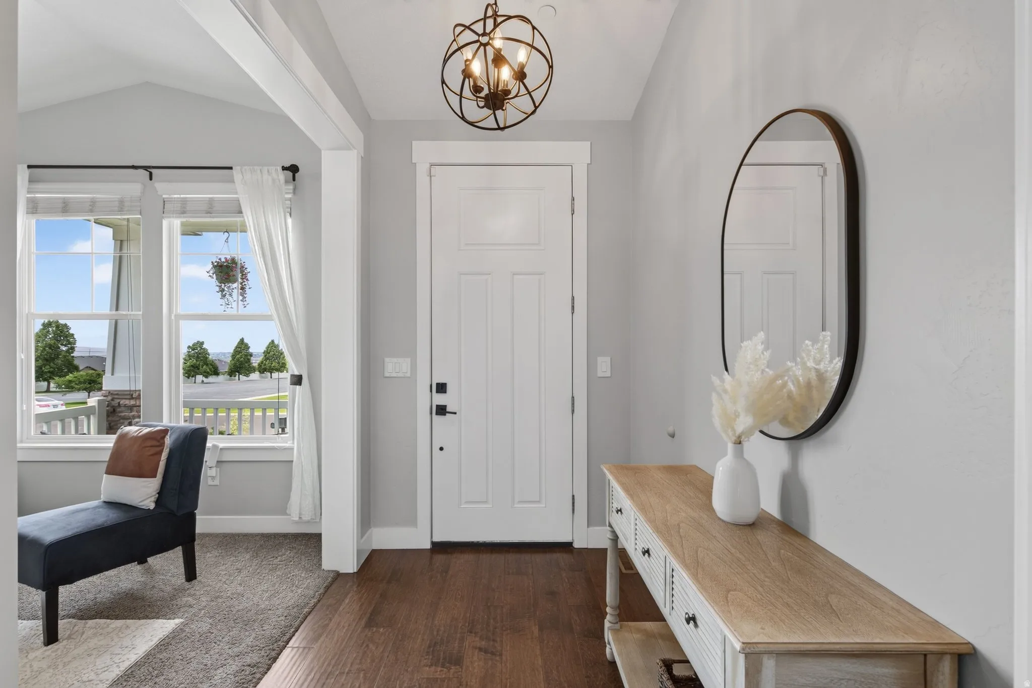 Entryway featuring wood-finish flooring, a white paneled door, and an overhead orb chandelier