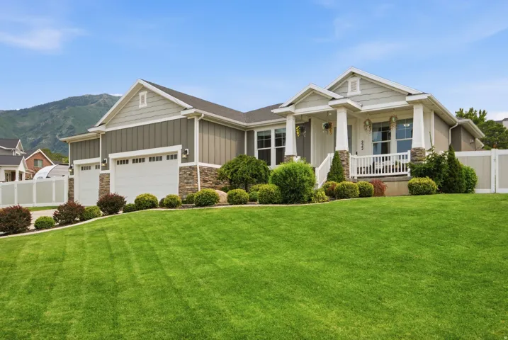 Welcoming Elk Ridge rambler with covered front porch, three-car garage, fully manicured landscape, RV parking, and beautiful Mt. Loafer backdrop.