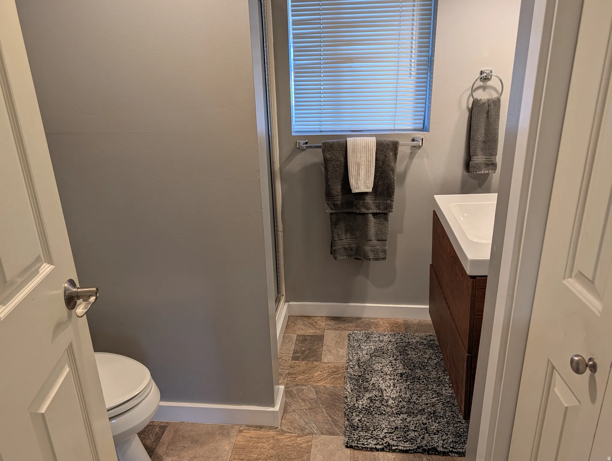 Full bathroom featuring a rectangular white sink, wood-finish vanity, and tiled flooring