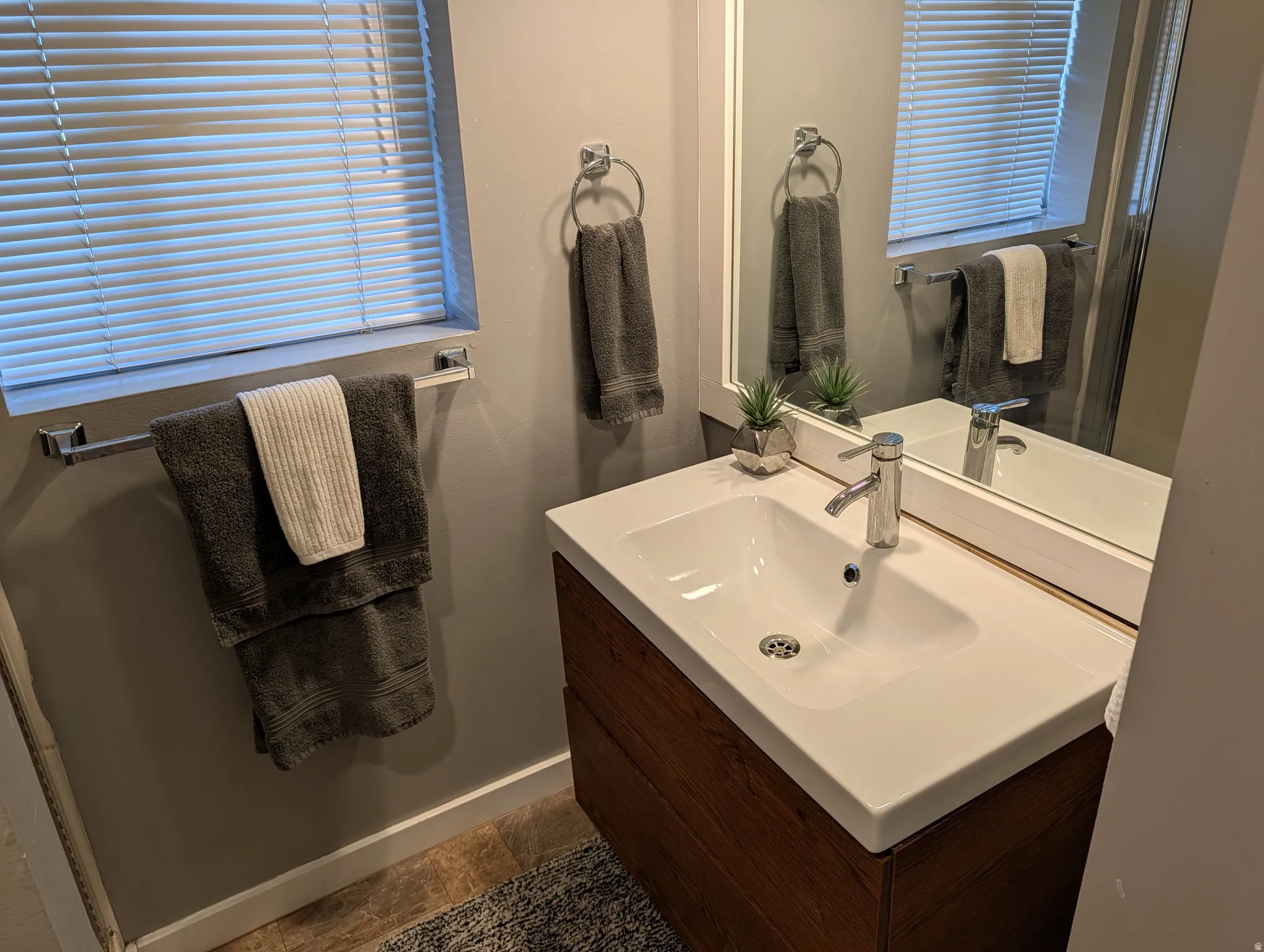 Modern bathroom featuring a floating vanity with a wood-finish cabinet and integrated rectangular sink