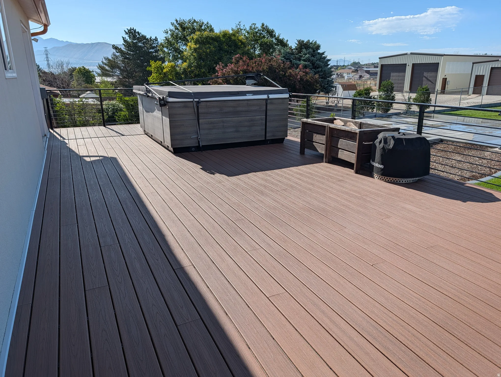Expansive outdoor deck featuring wood-finish composite flooring, a hot tub, and modern cable railings
