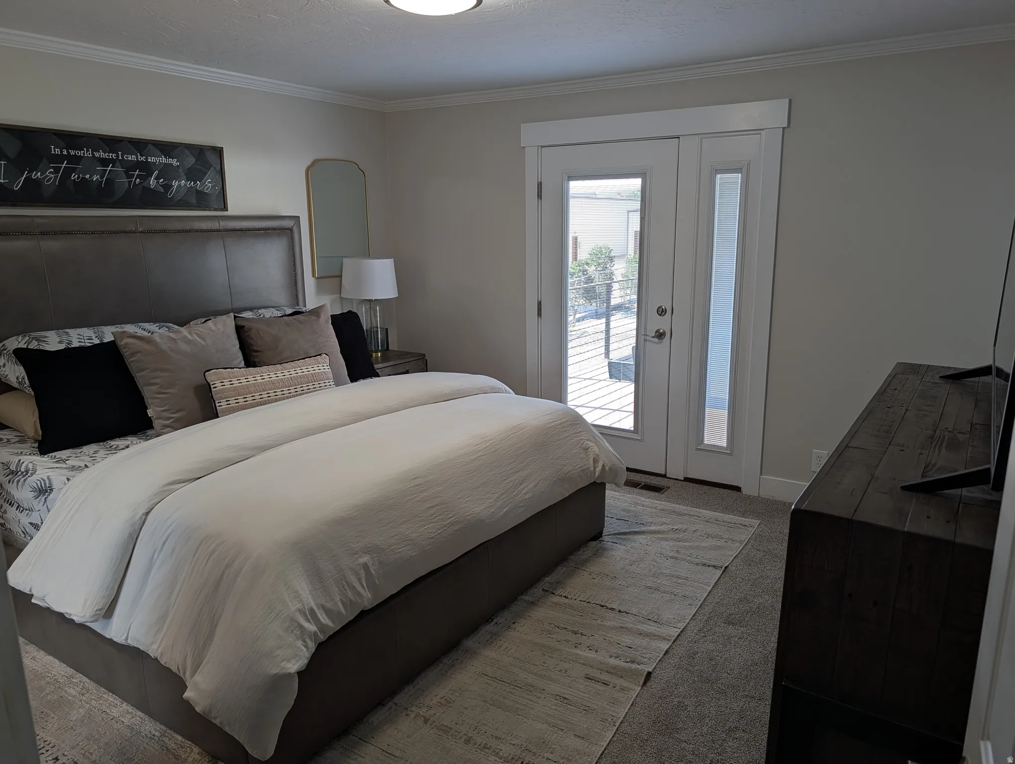 Bedroom featuring light gray wall paint, crown molding, and carpet flooring