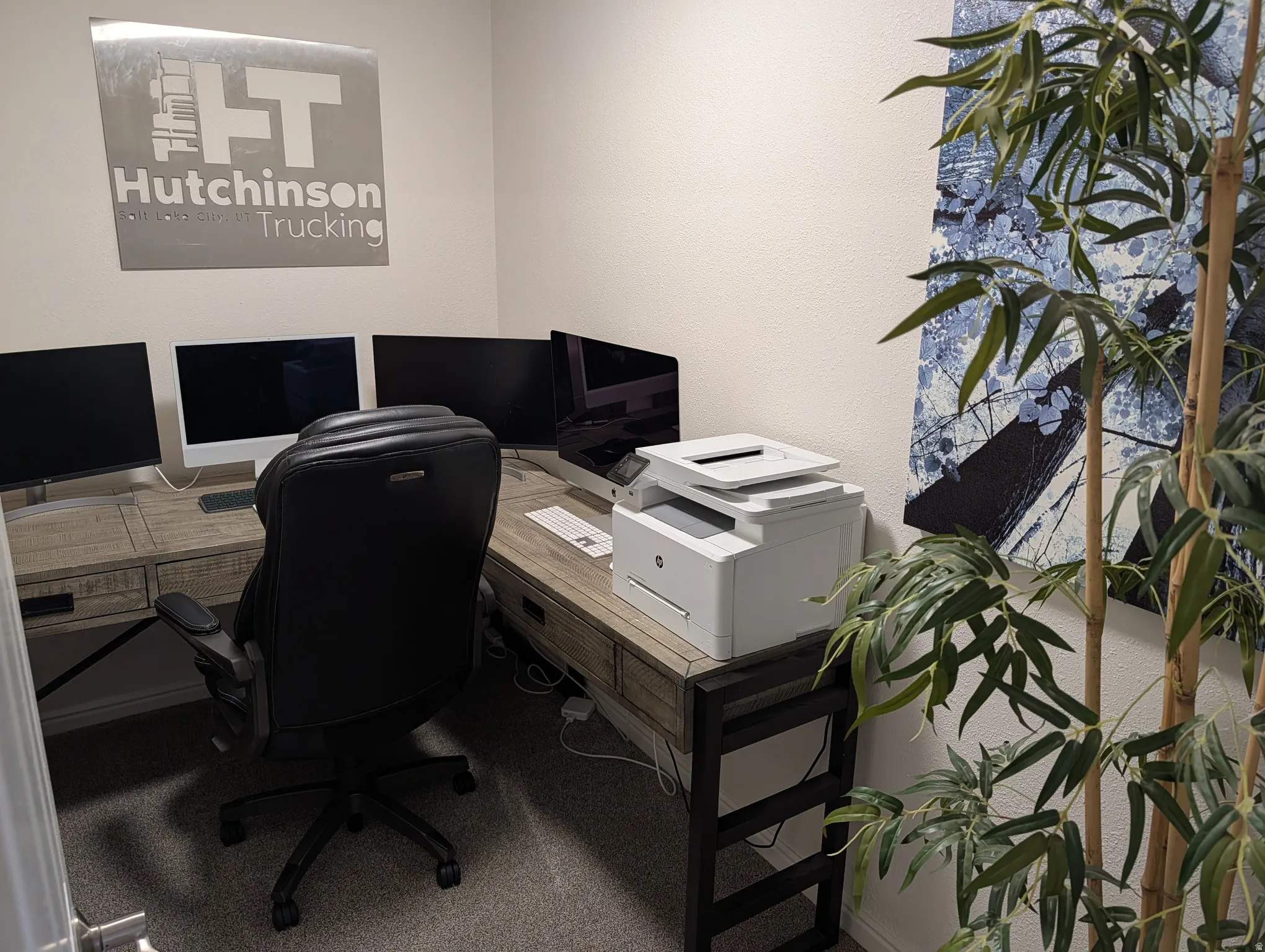 Dedicated room featuring textured walls, carpet flooring, and a corner desk with wood-finish surfaces and dark metal accents