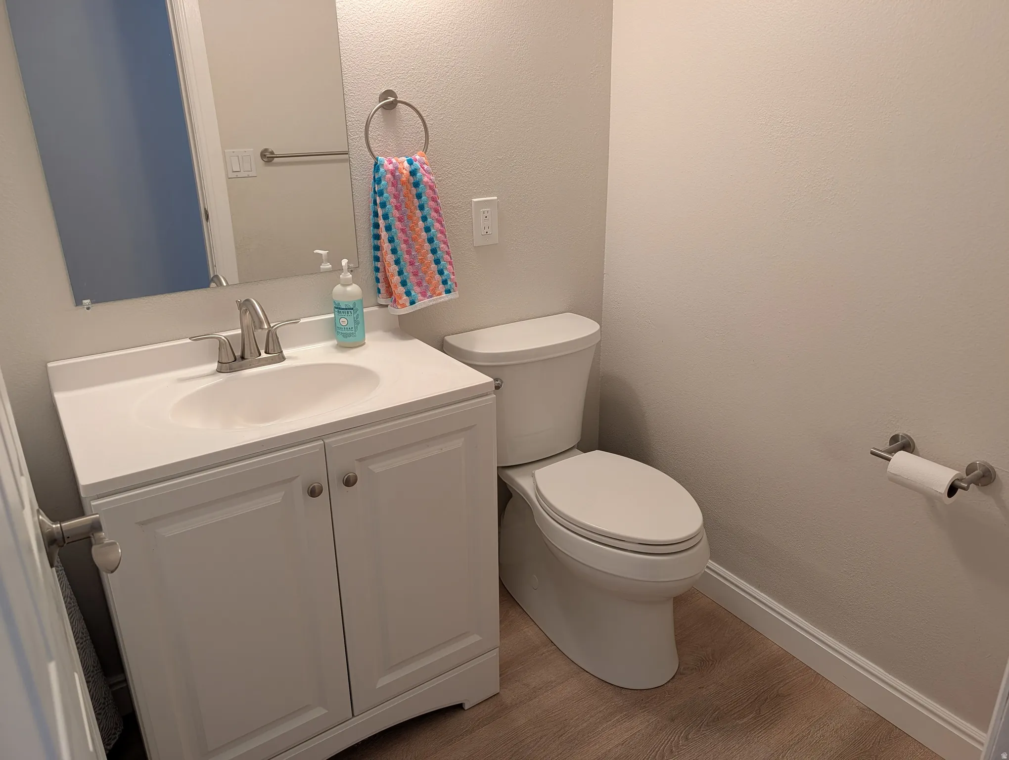 Bathroom featuring a white vanity with an integrated sink, brushed nickel faucet, and a wall-mounted mirror