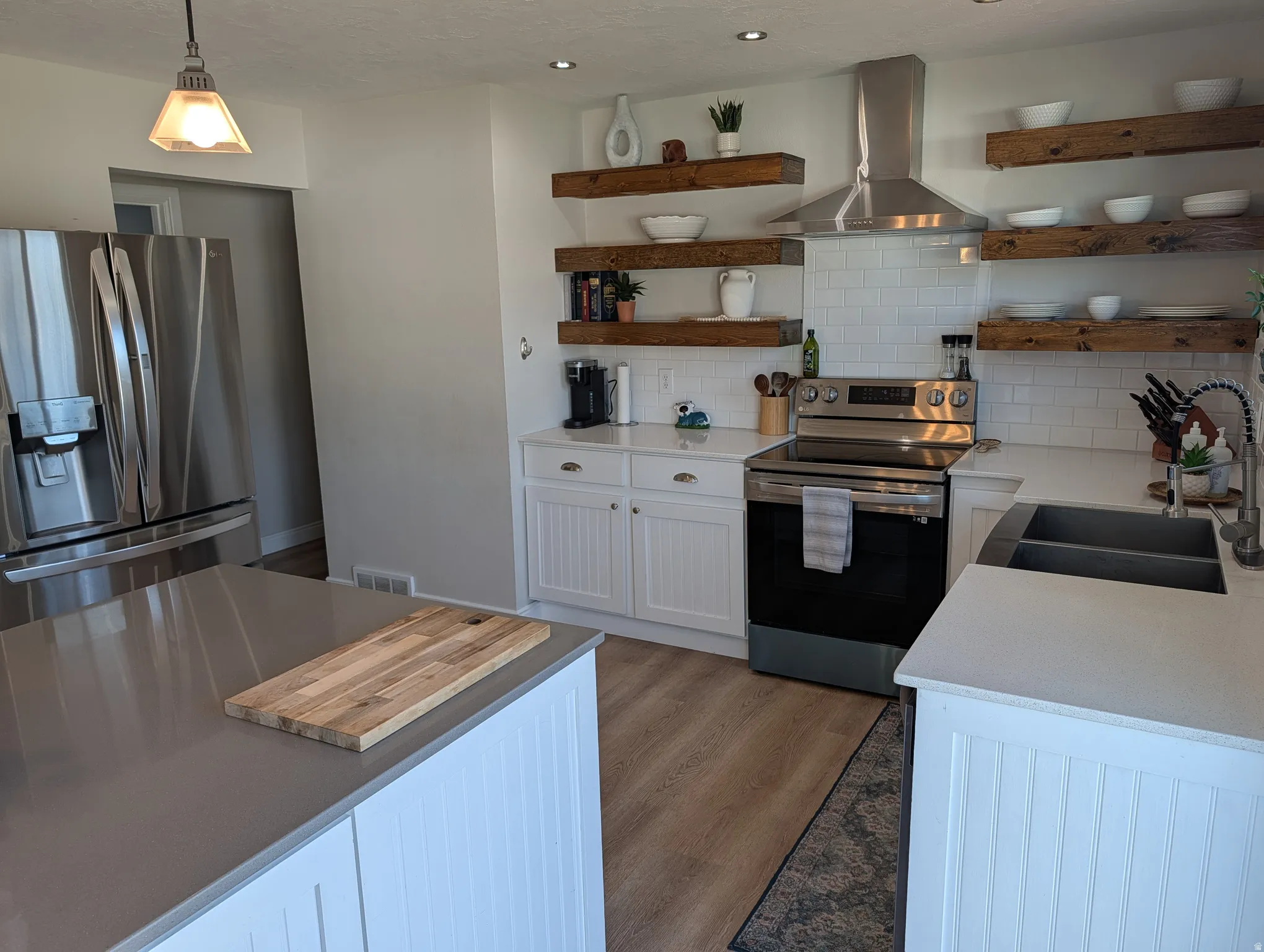 Modern kitchen featuring white shaker-style cabinetry, wood-finish flooring, and a stainless steel appliance suite