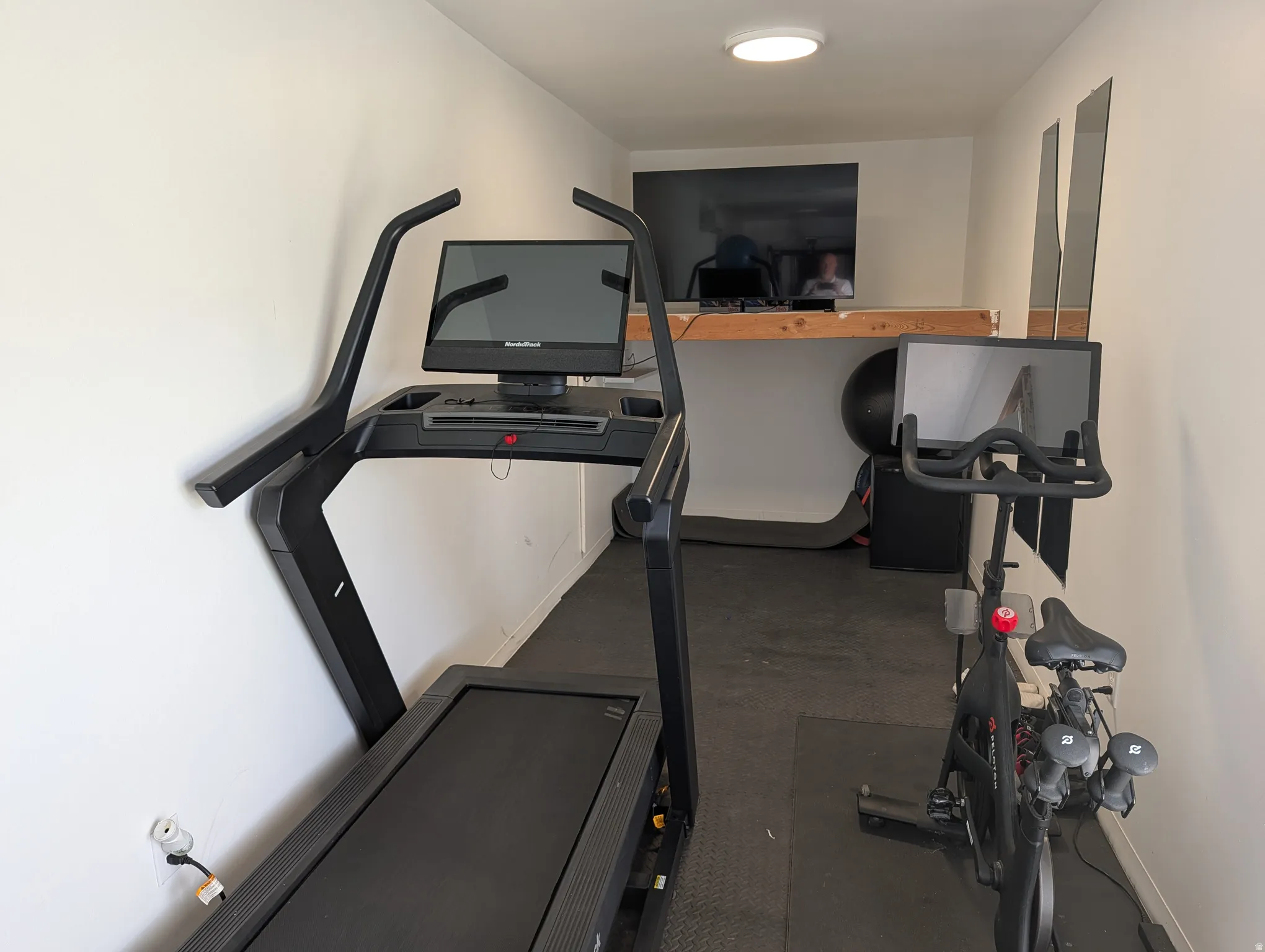 Dedicated fitness room with white walls and a ceiling-mounted light fixture
