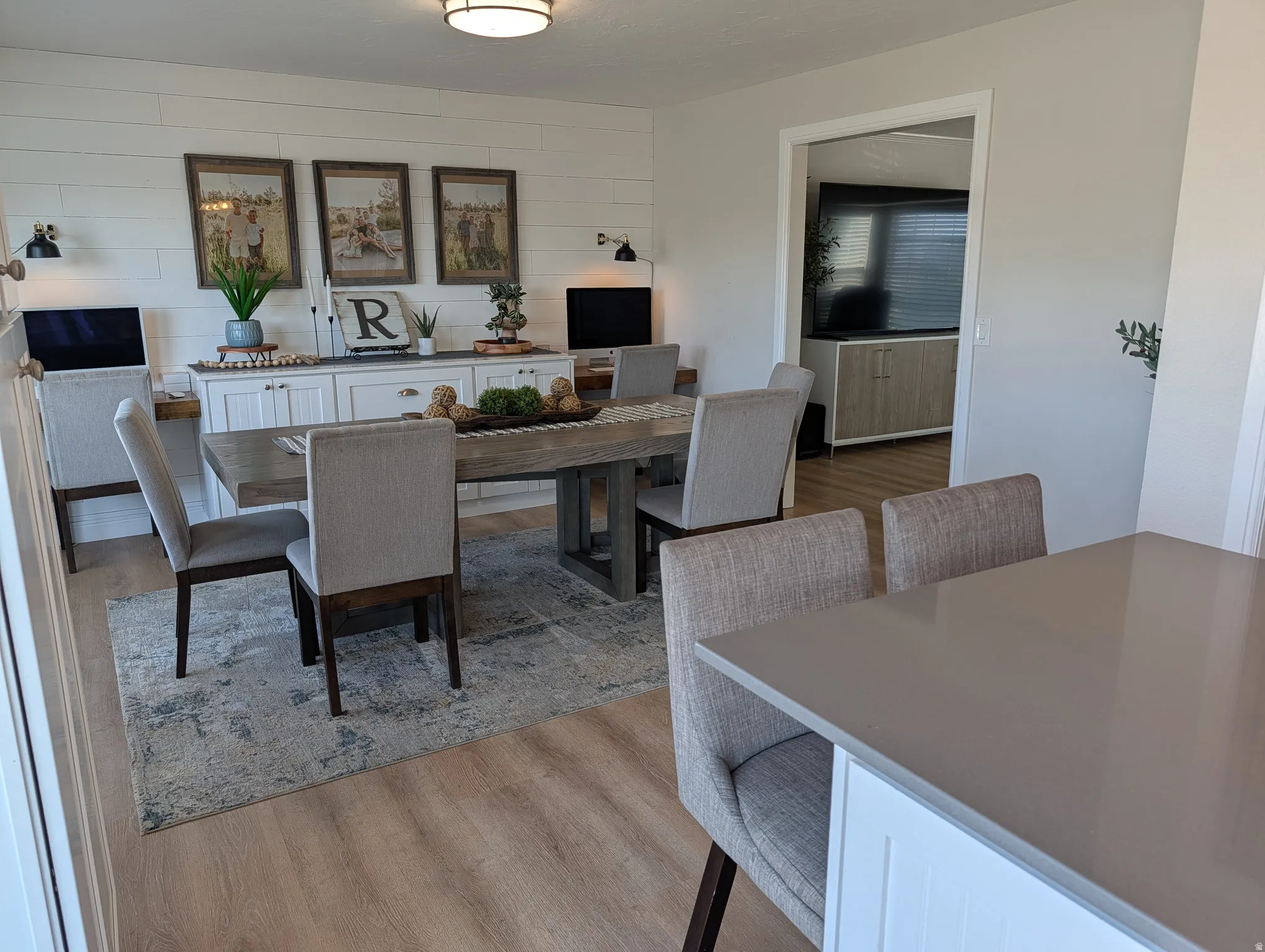 Spacious dining area featuring wood-finish flooring, a shiplap accent wall, and a built-in buffet with storage