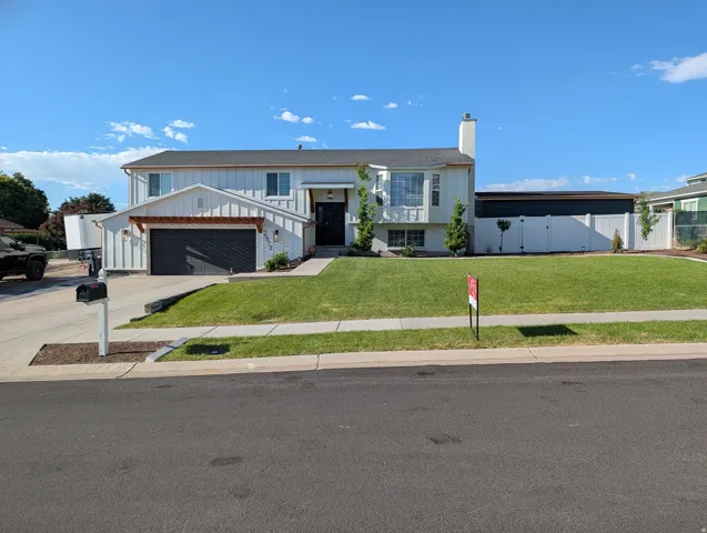 Contemporary residence featuring white vertical siding and a dark gray garage door