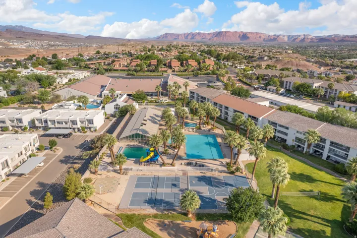 Expansive community grounds featuring multiple outdoor swimming pools, sports courts, and mature palm trees