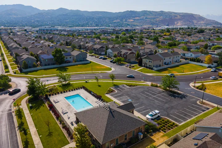 Community pool with integrated sun deck and surrounding green space, accompanied by a dedicated parking area