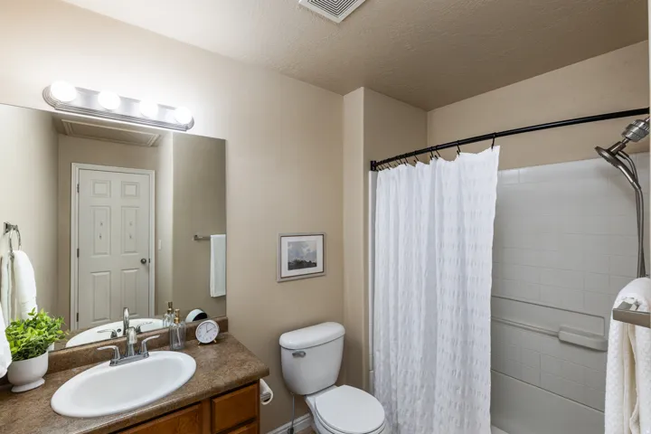 Bathroom featuring a wood-finish vanity with an integrated sink, a large wall mirror, and a shower-over-tub combination with white subway tile surround