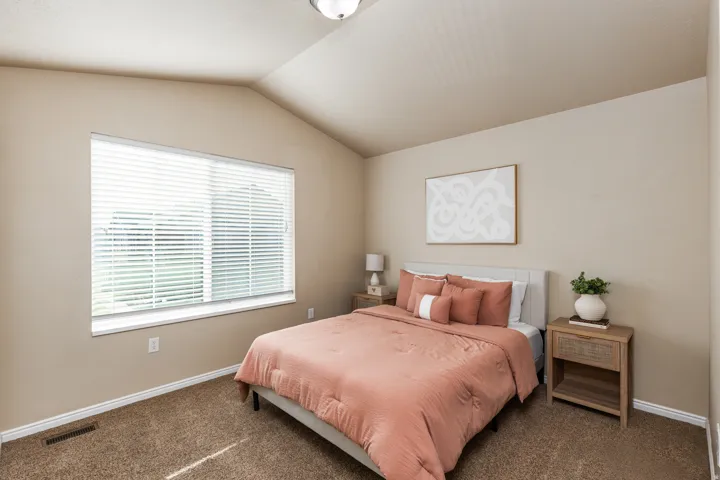 Bedroom featuring a vaulted ceiling and a large window with horizontal blinds