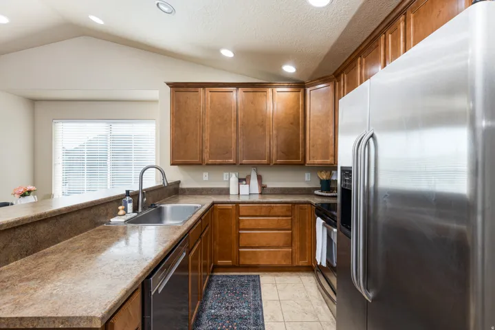 Kitchen featuring wood-finish cabinetry, stainless steel appliances, and a double basin sink with a high-arch faucet