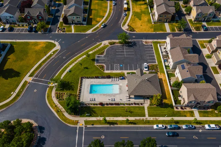 Community pool with a surrounding patio, multiple lounge chairs, and a covered pavilion