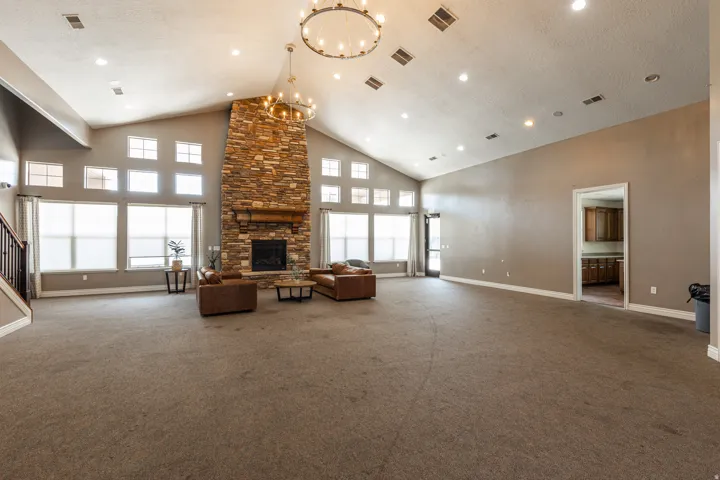 Spacious great room featuring a floor-to-ceiling stone fireplace, vaulted ceilings, and extensive window arrays