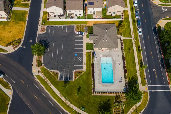 Community amenity area featuring a rectangular swimming pool, surrounding patio, and dedicated parking lot