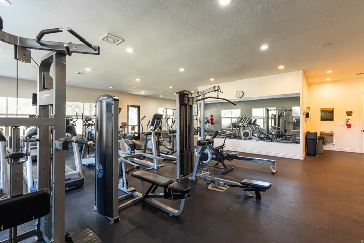 Fitness center featuring various exercise machines, recessed lighting, expansive mirrored wall, large windows, and durable floor surfacing