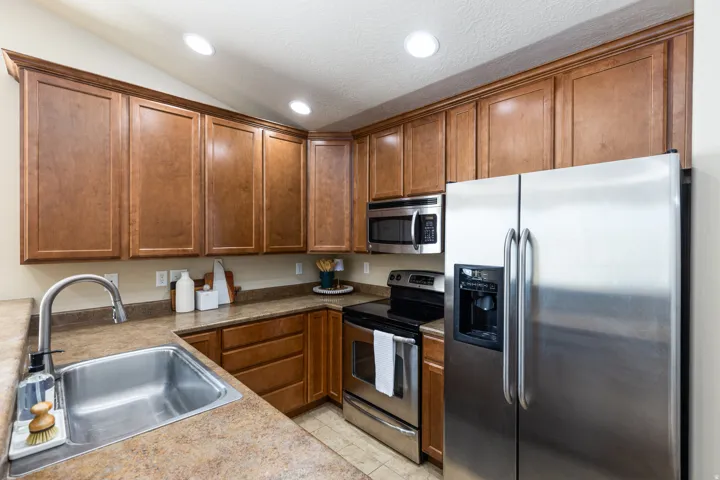 Kitchen featuring extensive wood cabinetry, stainless steel appliances, a double basin sink with a high-arc faucet, ample countertop space, and recessed lighting
