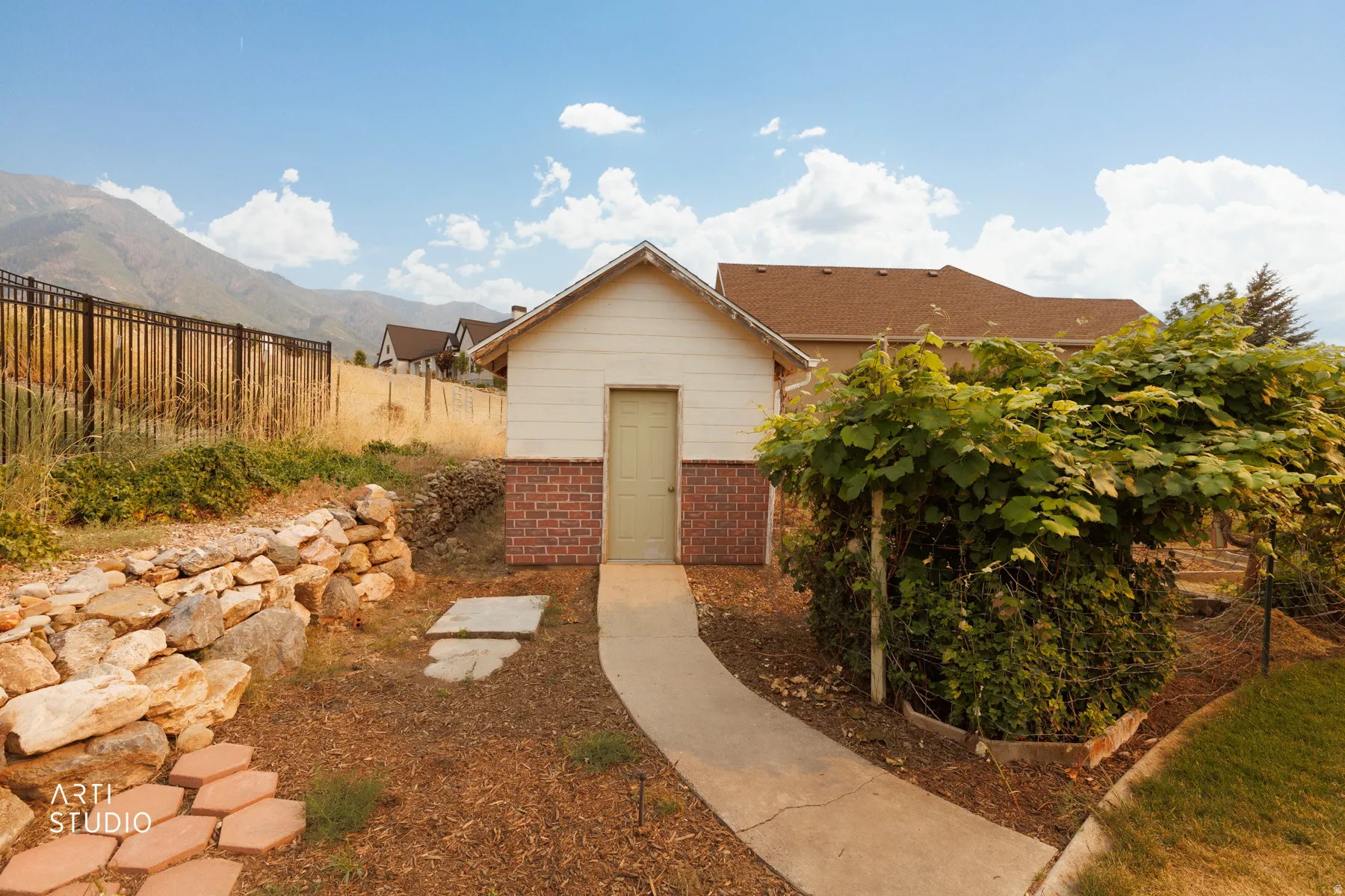 Detached outbuilding featuring a light-colored exterior and brick-finish siding