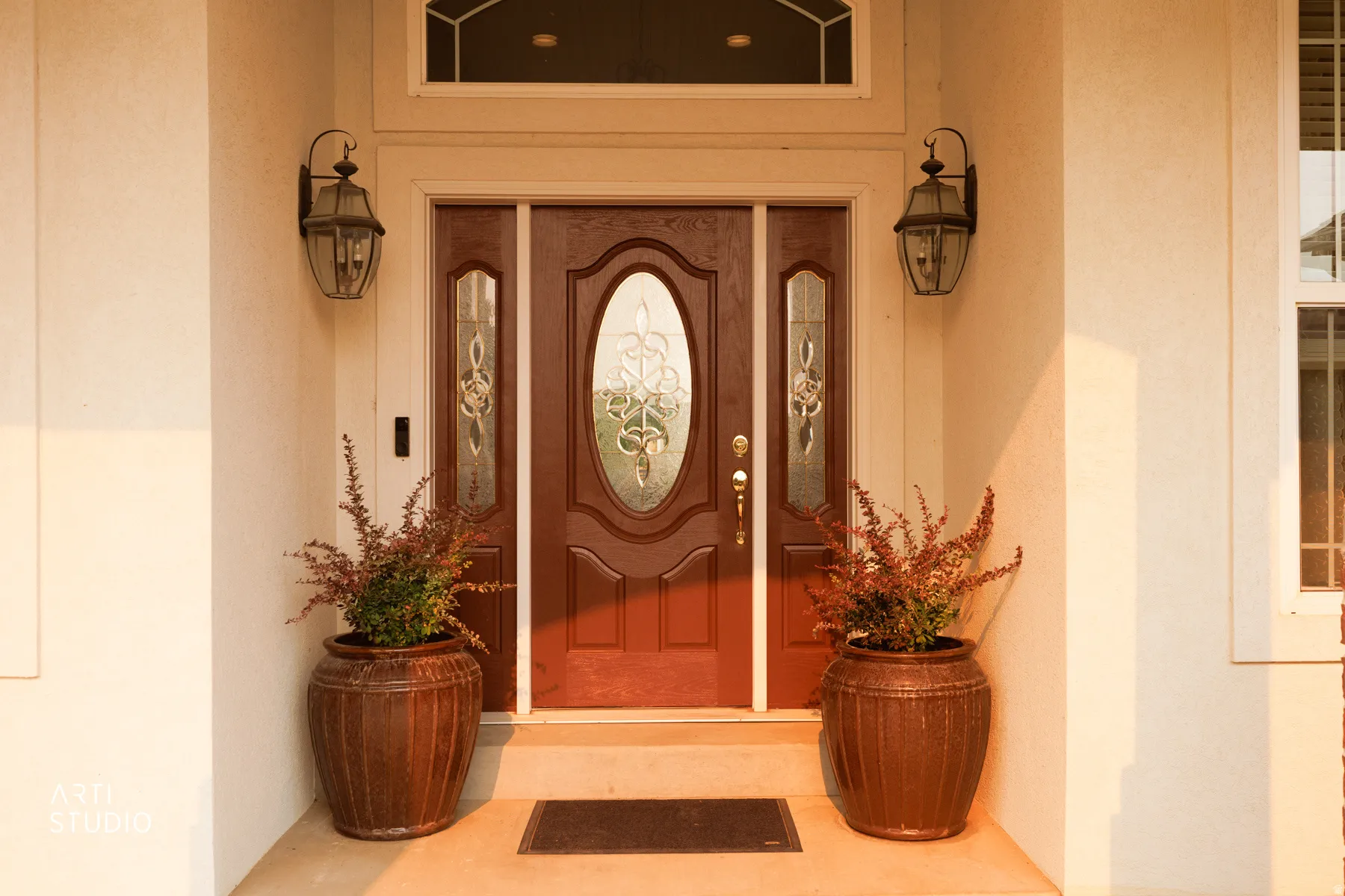 Entryway featuring a wood-panel door with decorative glass inserts, sidelight windows, and an arched transom window
